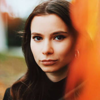 Photo by https://byabduls.com/work close up portrait of a girl looking into camera with orange leaf in foreground