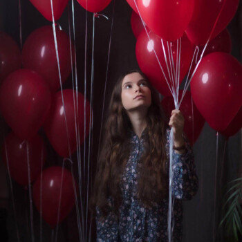 Photo by https://www.finnsquare.com/ photo of a girl looking up at red balloons that she is holding
