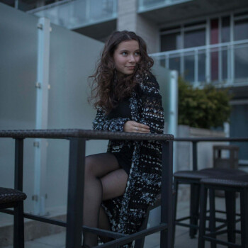 Photo by https://www.finnsquare.com/ picture of a girl sitting outside in dark clothing